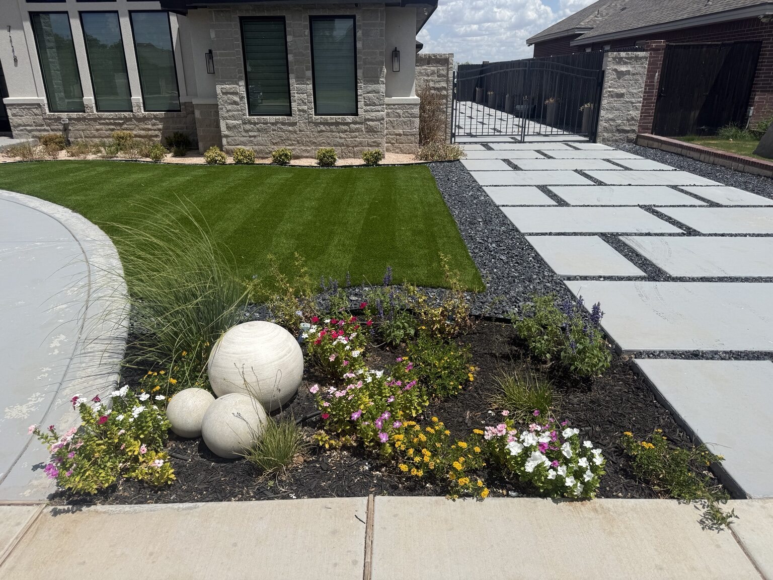 Completed front yard with turf, flower bed, rock, and concrete driveway
