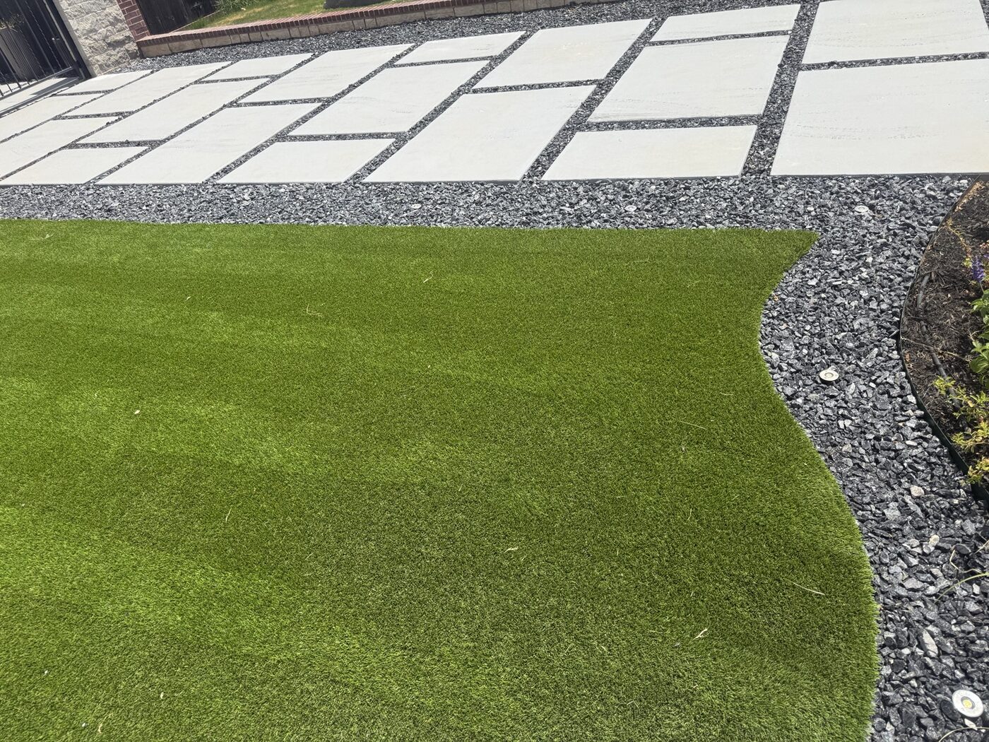 Artificial turf beside concrete pads and decorative rock